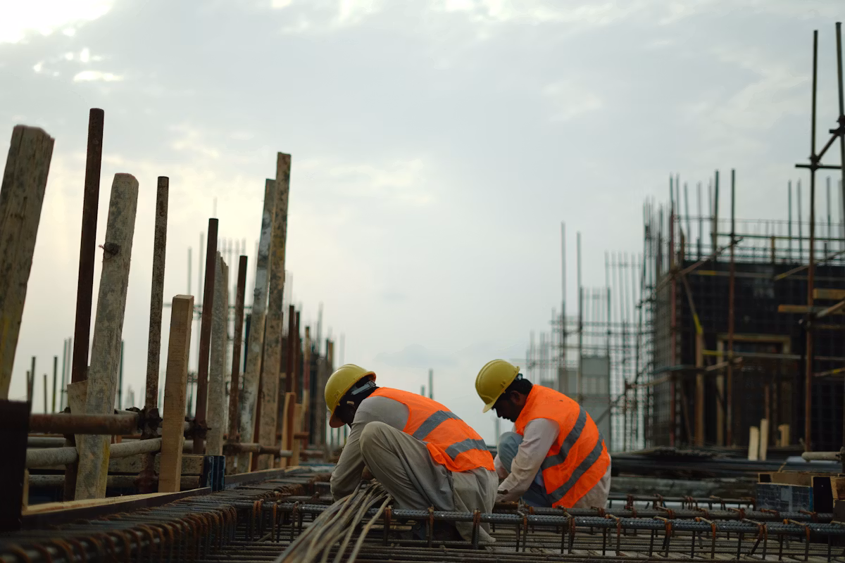 Construction workers in hard hats and safety vests on an active jobsite.